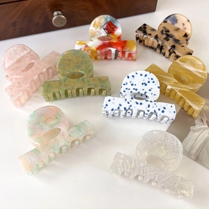 Close-up of various acetate shark hair clips with diverse colorful marble patterns