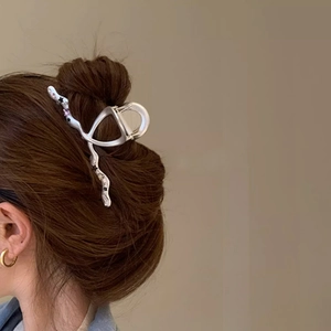 Silver metal star shark hair clip with wavy design on hair shown from a side view