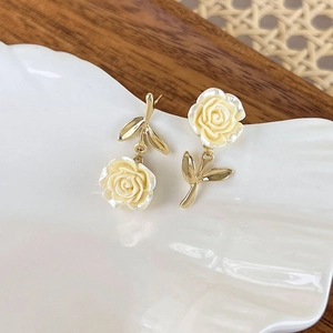 Detail shot of asymmetrical cream rose earrings with gold leaf and resin texture
