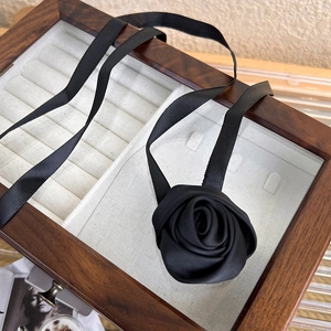 Close-up of a handmade black fabric rose choker with long satin ribbons on a jewelry box
