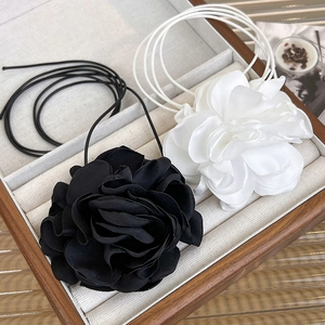 Detailed view of handmade black and white fabric camellia flowers with elegant silk ribbon