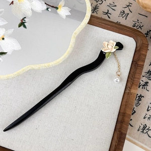 Détail d'épingle à cheveux noire en S avec fleur de muguet et pampille en perle élégante