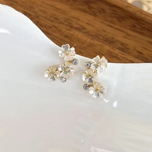 Macro detail of elegant flower earrings with white shell petals and crystal accents