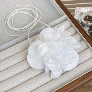 Close-up of white fabric rose flower choker with long ribbon in a velvet jewelry box