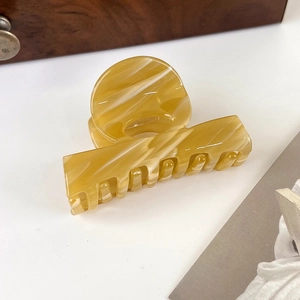 Detail view of an amber marble acetate hair claw clip with smooth resin texture