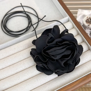 Close-up of a large black fabric rose choker featuring layered silk petals on a thin cord