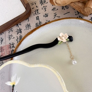 Détail d'un pic à cheveux en bois avec muguet, pompon de perles et motifs floraux