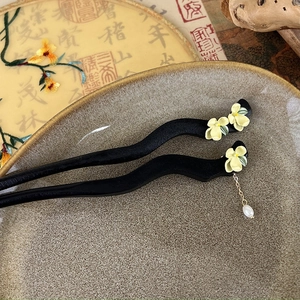 Detailed close-up of jasmine ebony hairpins with white pearl tassel and yellow flower detail