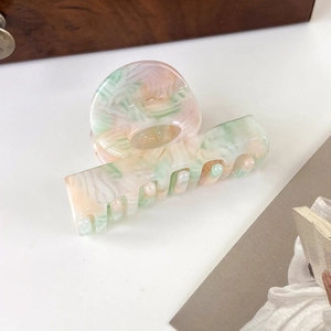 Detailed macro view of high-quality acetate hair claw with pastel pink and green marble texture