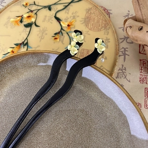 Close-up of sandalwood hair sticks with floral accents and pearl tassels on a Zen background