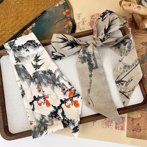 Detail view of ink wash painting silk hair scarf displayed on a traditional wooden tray