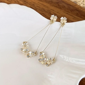 Detail of floral shell earrings with white petals and pearls on a ceramic dish