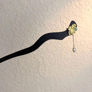Detail of ebony hair pin featuring yellow jasmine flower and hanging pearl tassel
