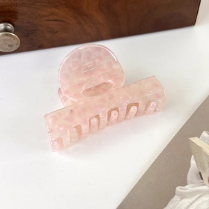 Detail view of pink acetic acid hair claw clip with semi-transparent spotted texture