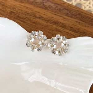 Macro shot of elegant shell flower earrings with gold metal and sparkling rhinestones