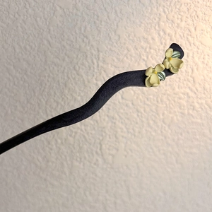 Detail of sandalwood hairpin with delicate yellow jasmine flowers for traditional styling