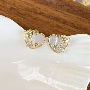 Macro detail of heart-shaped gold earring with rose design and pearl luster finish