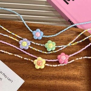 Gros plan de colliers de perles colorées avec pendentifs fleurs en résine sur plateau