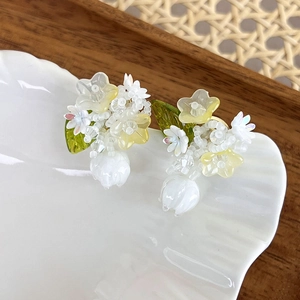 Detailed shot of handmade beaded flower earrings with pearl accents on shell tray