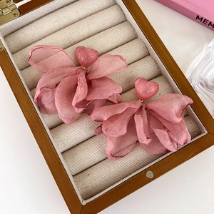 Sweet pink fabric flower earrings with heart studs on a wooden jewelry display case