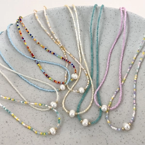 Detail of colorful beaded necklaces with a central freshwater pearl on a ceramic plate