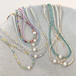 Detailed macro view of colorful seed bead necklaces with freshwater pearls in ceramic tray