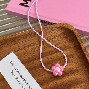 Bijou de téléphone en perles roses avec pendentif fleur sur plateau en bois