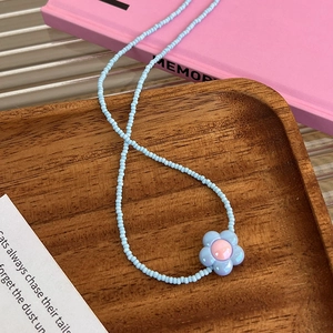Détail d'un collier de perles colorées avec pendentif fleur sur un plateau en bois