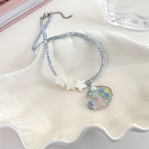 Macro detail of Y2K star and shell beaded necklace with blue crystal beads and pendant