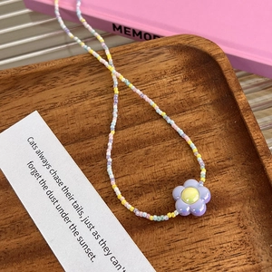 Détail d'un collier de perles en acrylique coloré sur un plateau à bijoux en bois