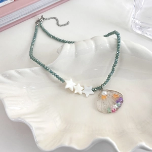 Close-up of star and shell beaded necklace on white porcelain dish with ocean-inspired detail