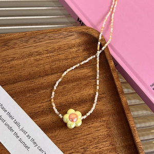 Détail d'un collier de perles avec pendentif fleur en acrylique sur un plateau