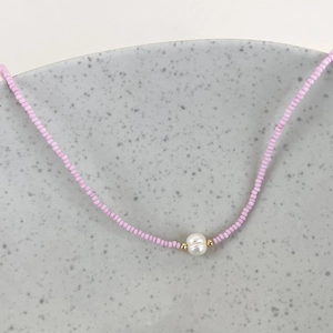Macro shot of pink seed beads and a natural freshwater pearl on a ceramic tray