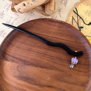 Detail of wooden hairpin with purple tulip glass pendant on a traditional tray