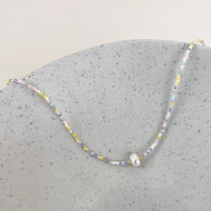 Detailed shot of handmade colorful macaron beads necklace with a central freshwater pearl