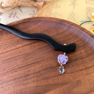Detail view of handmade wooden hair pin with purple lily flower glass pendant on a tray