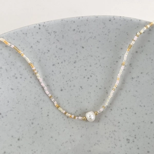 Macro shot of colorful seed beads and a natural freshwater pearl on an elegant necklace
