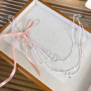 Close-up of pink ribbon bow and beaded multi-layer necklace with butterfly pendant