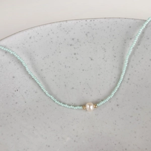 Detailed macro view of light blue seed bead necklace with center freshwater pearl accent