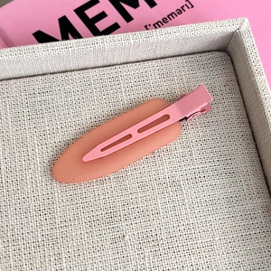 Macro view of a matte pink duckbill hair clip with translucent jelly finish on fabric