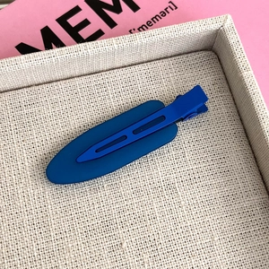 Detailed close-up of a matte dark blue hair clip with hollow design on a textured tray
