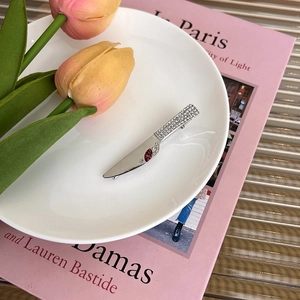 Gros plan d'une pince à cheveux couteau Y2K argentée avec strass roses sur une assiette