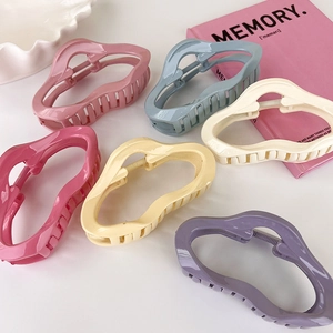Detail of colorful irregular acrylic hair claws in vibrant candy colors on white tray