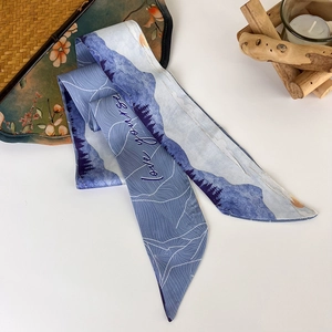 Macro shot of silk twilly scarf with blue landscape print and love yourself text