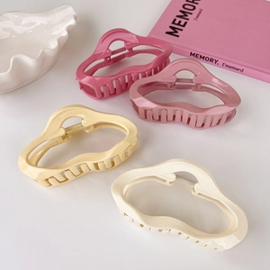 Flat lay of four irregular cloud-shaped matte acrylic hair claws in pastel colors