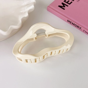 Detail shot of a cream white irregular large cloud hair claw with sturdy metal spring