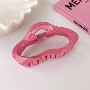 Detailed view of a glossy rose pink cloud-shaped claw clip on a stylish decorative tray