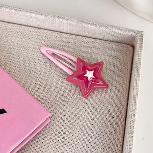 Dettaglio del fermaglio BB in metallo rosa con design a stella y2k su vassoio