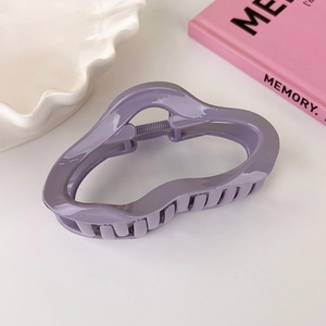 Close-up of purple acrylic cloud hair claw clip on white plate with a memory book