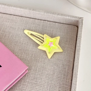 Dettaglio del fermaglio a stella Y2K con stelle in resina rosa e verde su base metallica